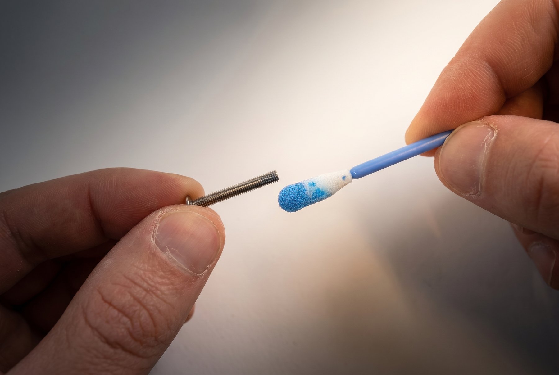 Loctite being applied to the last few threads of a cover screw with a swab
